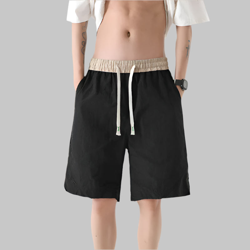 Person wearing black shorts with a beige drawstring on a beige background
